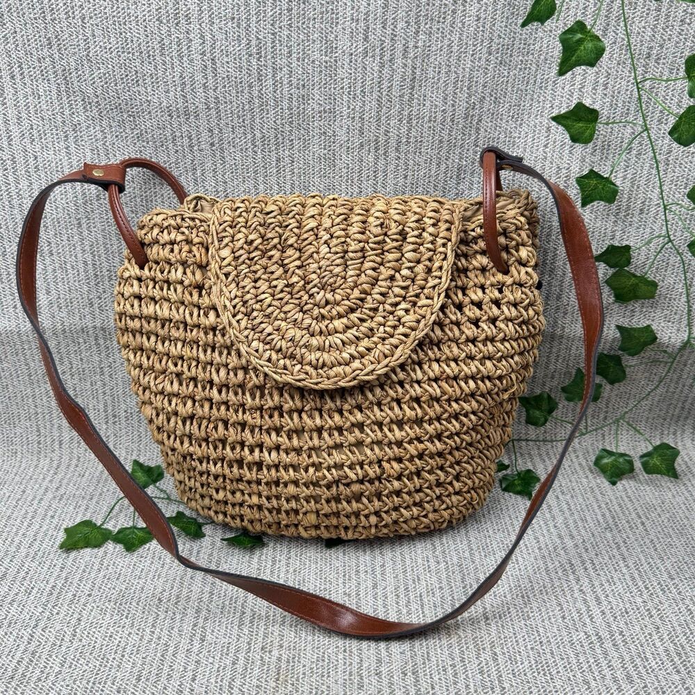 A & W vintage straw crossbody bag with brown leather straps and a flap closure.